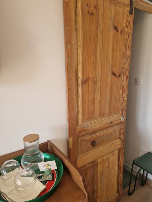 Porte en bois et table avec verres d'eau dans une chambre de la maison d'hôtes Maisonaurinko, Thénon