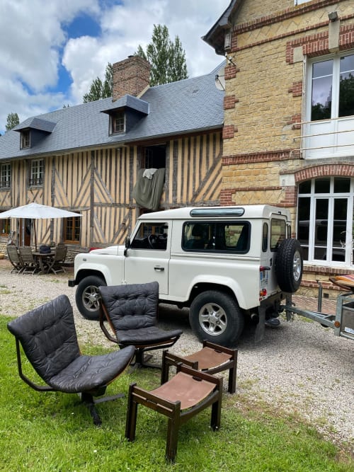 White Land Rover parked at Domaine de Blanvatel, a French countryside B&B in Saint Pierre en Auge, with black chairs and
