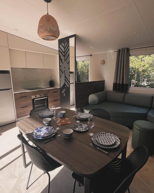 Coin repas moderne du Mobil-Home l'Arbousier au Maquis Plage, Corse, avec table en bois, chaises noires, cuisine et