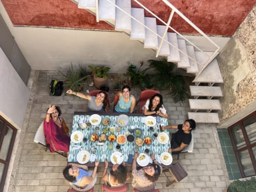 Grupo disfrutando juntos en el patio de Casa Tuch en Mérida, vista aérea con gastronomía local y plantas