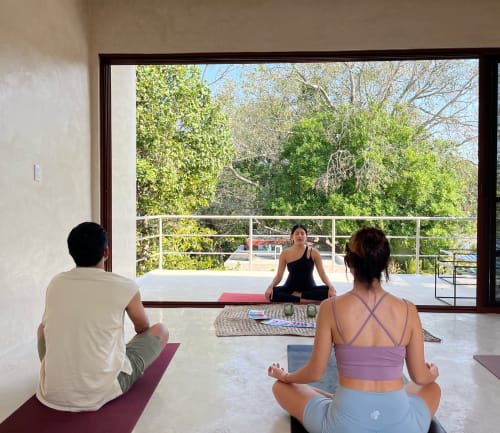 Clase de yoga en Casa Tuch, una posada en Mérida, con estudiantes meditando sobre tapetes con vista a exuberantes jardines