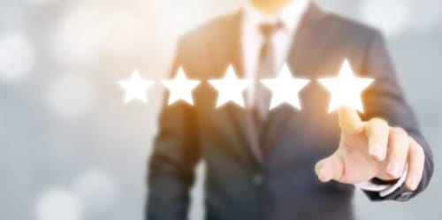 Homme d'affaires touchant un affichage de notation cinq étoiles, représentant l'excellent service de l'hôtel La Maison du Plaisir à Isigny-sur-Mer