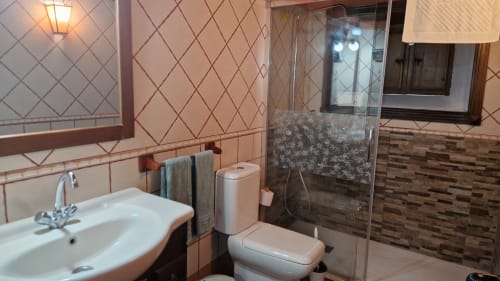 Modern bathroom at Casonas de Marengo cottage in Icod de los Vinos with sink, toilet, glass shower enclosure and tiled walls