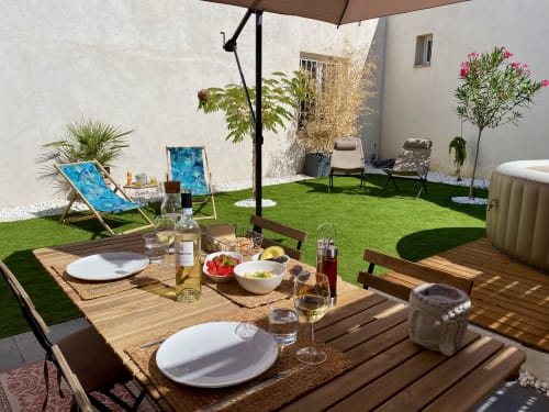 Espace de repas en plein air dans le jardin de la villa Tiny Harmony à Venelles, France avec table, chaises, parasol et transats