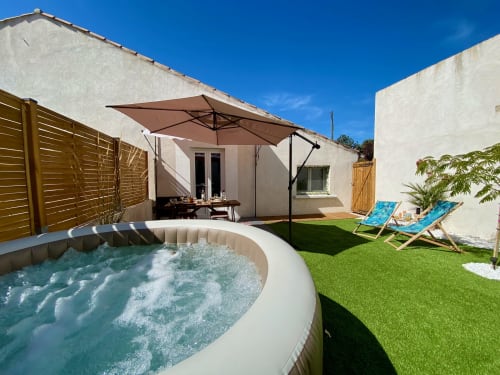 Jardin de la villa Tiny Harmony avec bain à remous, transats et parasol sous le ciel bleu à Venelles, France