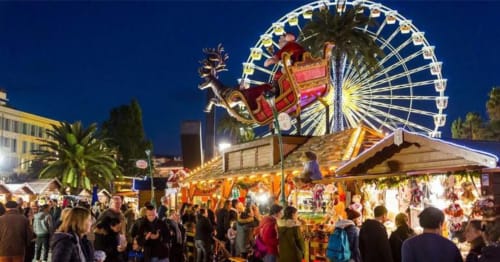 Joli marché de Noël nocturne avec grande roue illuminée et chalets festifs près de l'Hôtel De La Fontaine