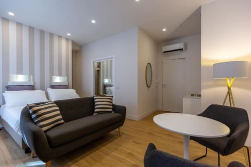 Suite moderna a Casa Lounge Istria di Cagliari con parete a righe, divano nero, biancheria bianca e design contemporaneo
