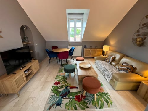 Chambre mansardée moderne à La Barbizonaise avec accents colorés, canapé en cuir et fenêtre de toit