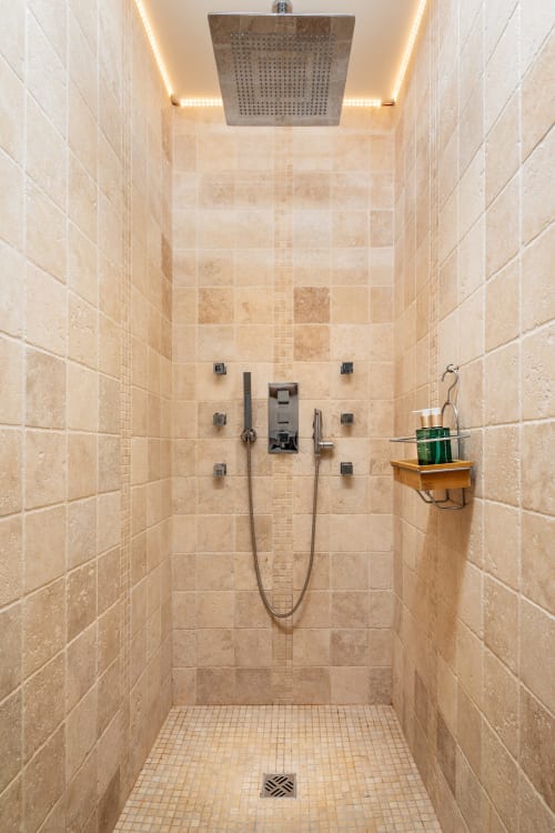 Moderne luxe douche met regendouchekop, beige travertijnen tegels en ambient verlichting in Domaine De Campagnac