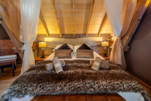 Luxe slaapkamer in Domaine De Campagnac met hemelbed, kunstbont plaid en sfeerverlichting in Carsac-Aillac, Frankrijk.