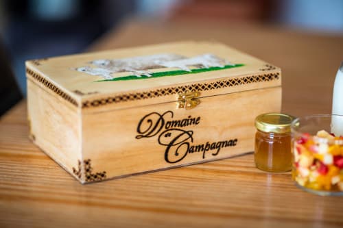 Houten kist van Domaine de Campagnac met decoratief deksel en koperen scharnieren op houten ondergrond