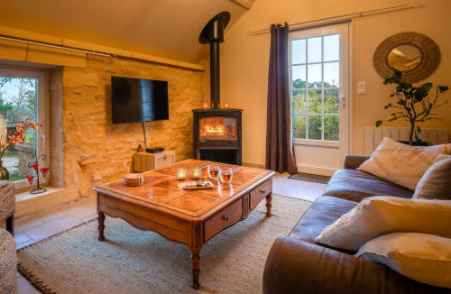 Gezellige woonkamer in Domaine De Campagnac met houtkachel, lederen zitplaatsen en uitzicht op het platteland