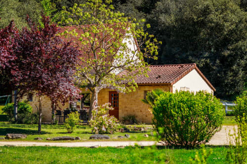 Het Catalpa-cottage op Domaine De Campagnac met stenen gevel, terracotta dak, omgeven door weelderige tuinen en klimop