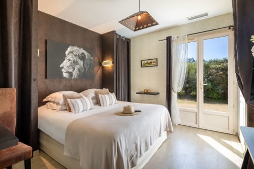 Slaapkamer van Le Catalpa cottage in Domaine De Campagnac met tuinuitzicht, leeuwkunstwerk, wit bed en openslaande terrasdeuren
