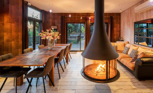 Luxe eetgedeelte met open haard, houten tafel, oranje zitplaatsen en tuinuitzicht bij Domaine De Campagnac