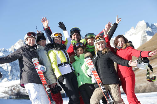 Groupe de skieurs célébrant à Domaine de l'Epigny à Grand Aigueblanche avec les Alpes enneigées en arrière-plan