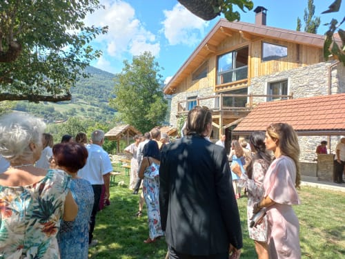 Invités rassemblés devant le Domaine de l'Epigny à Grand Aigueblanche, avec vue sur les montagnes et architecture alpine traditionnelle.