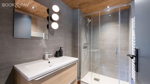 Salle de bain moderne du Domaine de l'Epigny avec meuble vasque suspendu, douche à l'italienne et éclairage ambiant