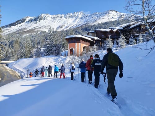 Des skieurs profitent des pentes enneigées du Domaine de l'Epigny à Grand Aigueblanche, entourés de montagnes majestueuses et d'un refuge alpin