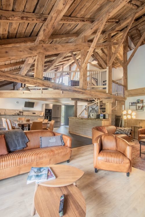 Intérieur rustique en bois du Domaine de l'Epigny avec sièges en cuir et espace de vie ouvert