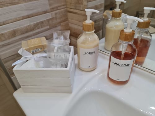 Articoli da bagno dell'hotel Raymihome Torino: lozione, sapone per le mani e prodotti per l'igiene personale in bottiglie di vetro con pompe in bambù