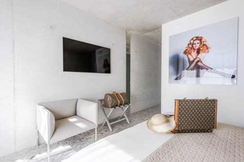 Modern hotel room at Le Pavillon M in Grignan with white seating, vintage luggage, and contemporary artwork