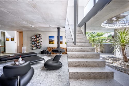 Modern living room at Le Pavillon M in Grignan with black furniture, concrete stairs, and natural light