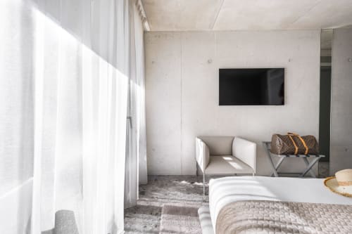 Modernes Hotelzimmer im Le Pavillon M in Grignan mit Bett, Sessel, Wandfernseher und natürlichem Licht von den Fenstern