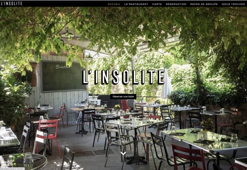 L'Insolite restaurant terrace in Lourmarin with lush greenery, dining tables, and red chairs