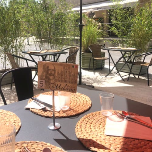 Outdoor terrace dining at AJOUCADOU B&B in Lourmarin with laid tables, woven placemats, and lush green bamboo screening.