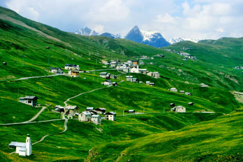 Villaggio alpino immerso in prati verdeggianti con vette innevate, Livigno, Italia