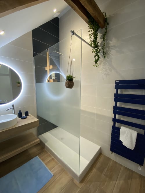 Salle de bains moderne au Lady Jule B&B avec douche à l'italienne, miroir lumineux, meuble lavabo en bois et sèche-serviettes noir chauffant