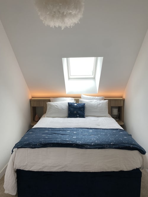 Chambre mansardée moderne au Lady Jule B&B avec fenêtre de toit, oreillers blancs, literie bleu marine et éclairage ambiant