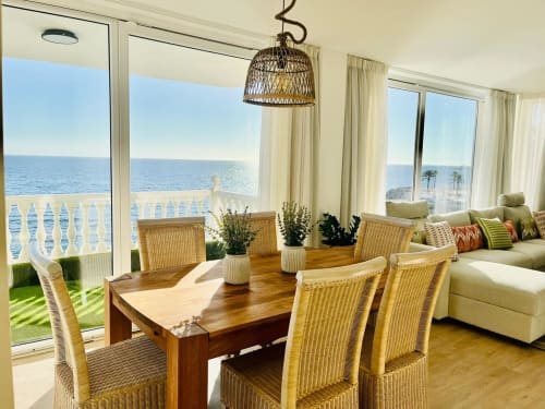Sunset ocean view suite in Arguineguín with dining area, wicker chairs, wooden table, and panoramic sea views through