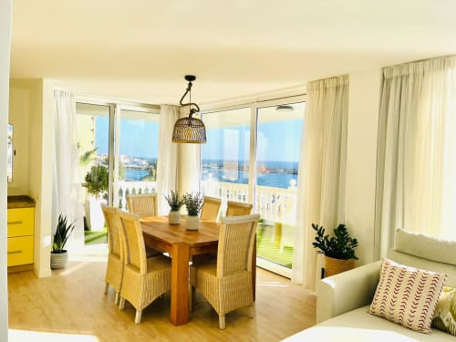 Bright Family Suite with wooden dining table, ocean views from balcony, beige curtains, and coastal décor in Arguineguín