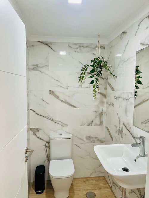 Modern bathroom in Sunset ocean view suite with marble tiles, white sink, toilet, and hanging plant in Arguineguín