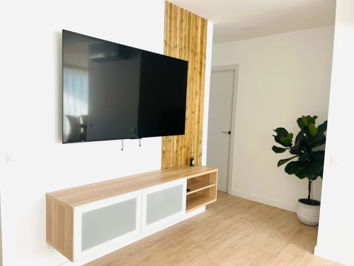 Modern family suite in Arguineguín with wall-mounted TV, wooden entertainment unit, and potted plant in bright, contemporary
