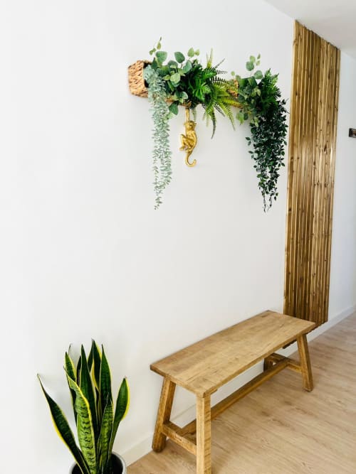 Modern apartment foyer with wooden bench, white walls, decorative hanging plants with ferns and gold monkey accent, ocean