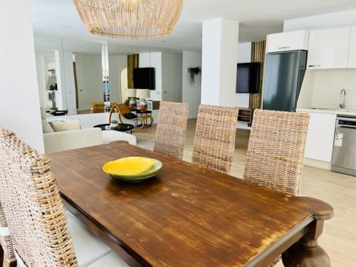Modern dining area with wooden table, woven chairs, and open kitchen in Arguineguín family suite apartment with ocean views