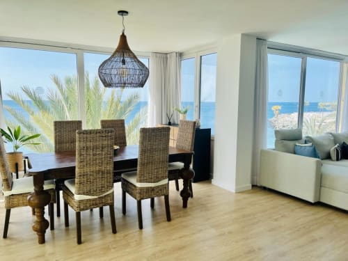 Bright ocean-view dining room with wicker chairs, pendant light, and sea vista in Arguineguín suite
