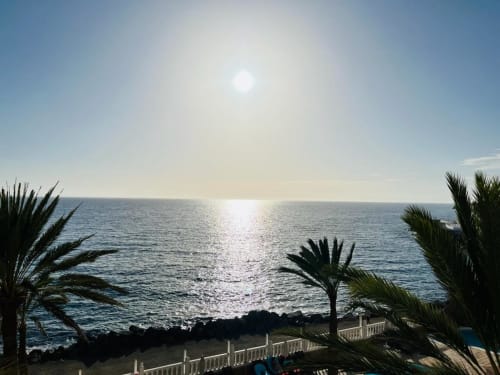 Sunny ocean view from Sunset Family Suite in Arguineguín with palm trees and beach balcony