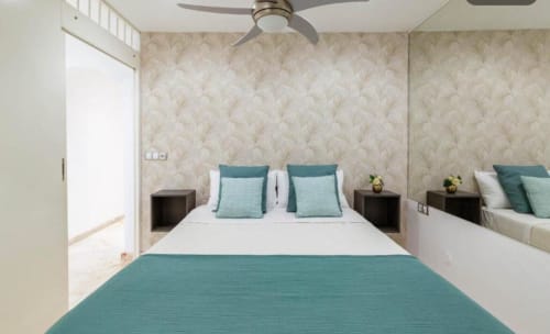 Modern 1-bedroom apartment in Arguineguín with teal accents, ceiling fan, and sea-view wallpaper decor