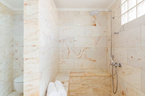 Modern bathroom with cream marble tiles, walk-in shower, and toilet in Arguineguín apartment