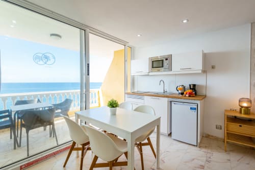 Bright studio apartment with sea view balcony, kitchenette, white dining table, and ocean vista in Arguineguín