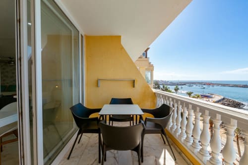 Sunset ocean view balcony with sea views, black chairs, white table overlooking Arguineguín harbor