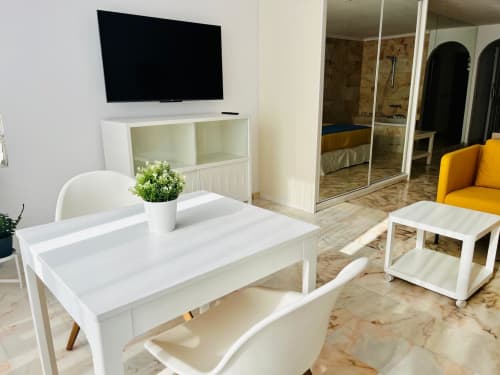 Modern studio apartment living area with TV, white furniture, and sea view in Arguineguín