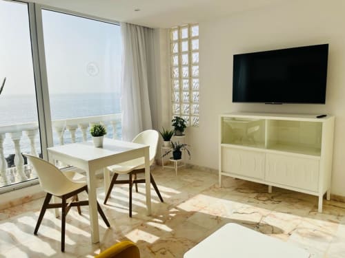 Modern studio apartment with ocean view, flat-screen TV, dining table, and sea-facing balcony in Arguineguín
