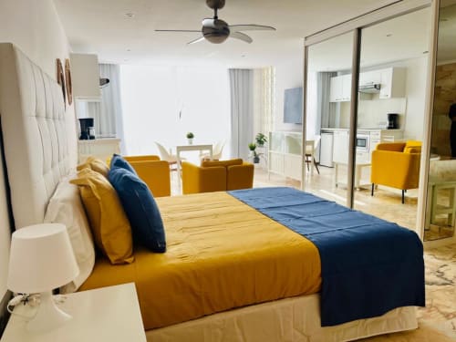 Modern studio apartment in Arguineguín with yellow and blue bedding, ocean view, ceiling fan, and open-plan living space