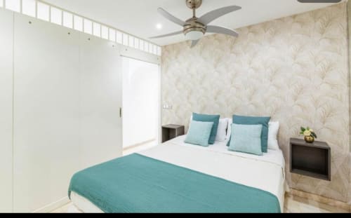 Modern bedroom with teal accents, patterned wallpaper, and ceiling fan at Sunset ocean view hotel in Arguineguín