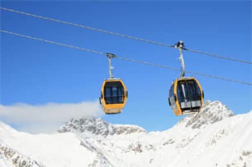 Yellow cable car cabins above snow-covered mountains at Livigno ski resort